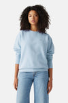 Light blue crewneck sweatshirt by [brand not provided], featuring soft cotton blend fabric, relaxed fit, and small chest logo, worn with light wash jeans in front view.