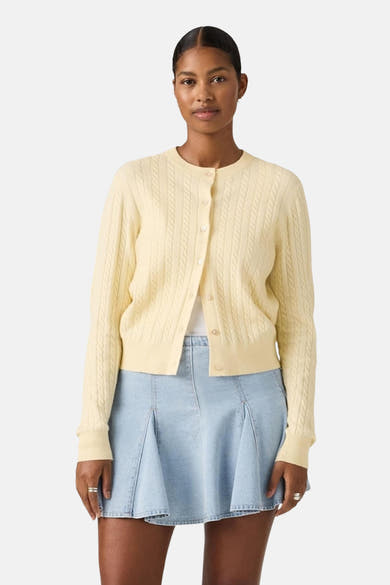 Gilet jaune clair de Levi's, avec des détails de torsades et porté avec une jupe en jean.
