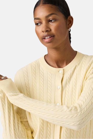 Gilet jaune de Levi's® avec texture tressée et fermeture boutonnée, porté avec des boucles d'oreilles créoles.