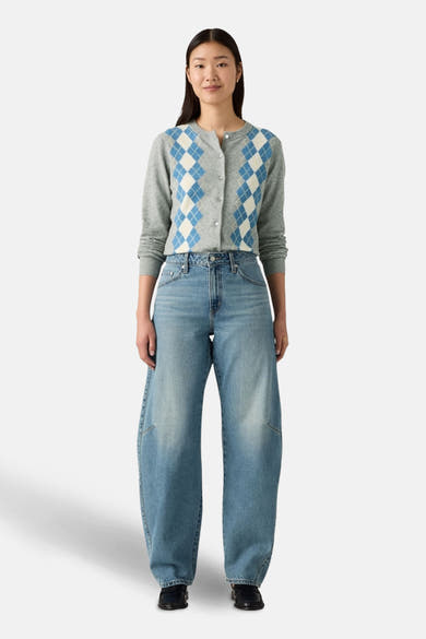 Jeans bleu clair amples de Levi's®, portés avec un cardigan à losanges et des mocassins noirs.
