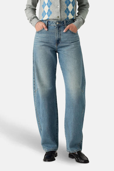 Jeans amples en denim bleu clair de Levi's, portés avec un cardigan à losanges gris.