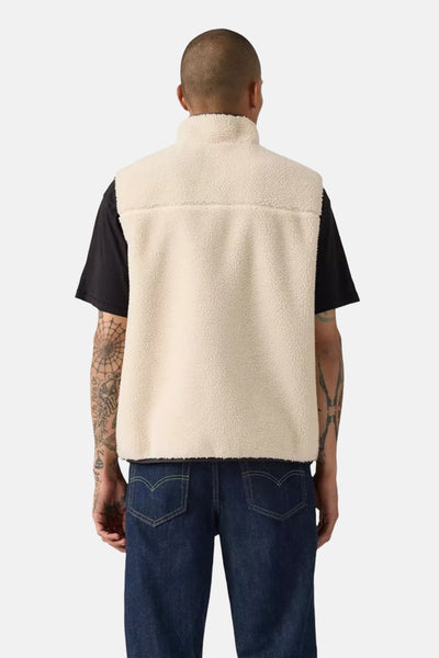 Veste sans manches beige de Levi's, avec une texture en polaire, portée sur un t-shirt noir et un jean bleu foncé.