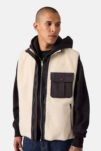 Veste sans manches beige en sherpa de Levi's, portée sur un sweat à capuche noir, avec une poche à rabat.