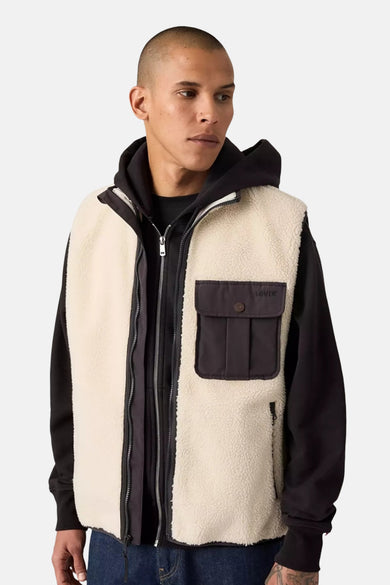 Veste sans manches beige en sherpa de Levi's, portée sur un sweat à capuche noir, avec une poche à rabat.