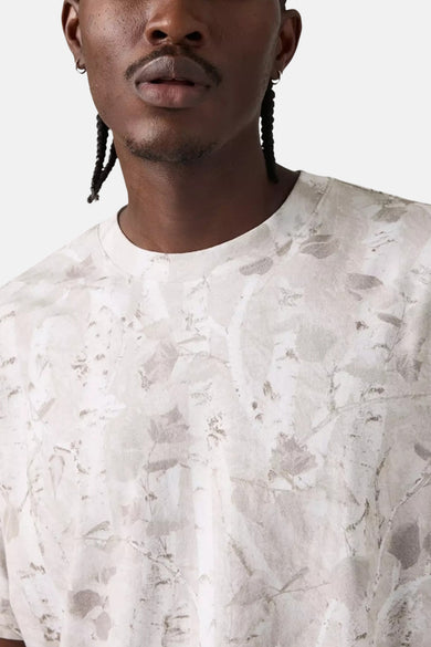 T-shirt beige à manches courtes de Levi's, imprimé avec des motifs végétaux ton sur ton, porté par un homme.