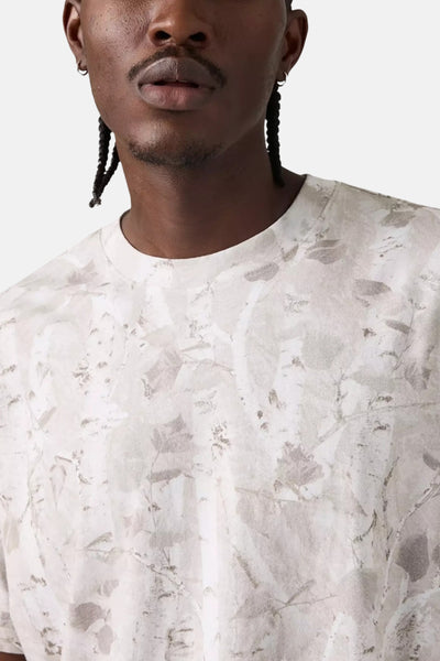 T-shirt beige à manches courtes de Levi's, imprimé avec des motifs végétaux ton sur ton, porté par un homme.
