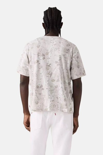 T-shirt beige à manches courtes de Levi's, avec un motif tacheté, porté avec un pantalon blanc.
