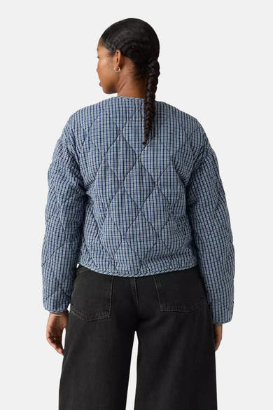 Veste courte bleue à carreaux, de Levi's®, avec un motif matelassé en losanges et un jean noir taille haute.
