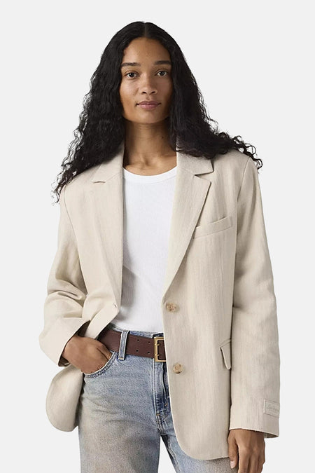 Beige blazer van Levi's®, met een gestructureerde pasvorm en een split aan de achterkant, gedragen met een grijze jeans.