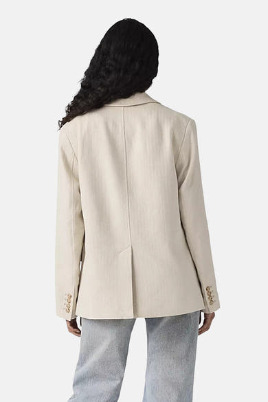 Blazer beige par Levi's®, avec une coupe structurée et une fente au dos, porté avec un jean gris.