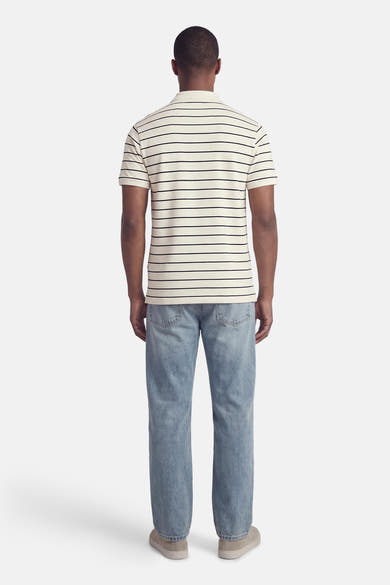 Wit gestreept poloshirt van Levi's®, gedragen met een blauwe spijkerbroek en casual suède schoenen, achtergezicht.