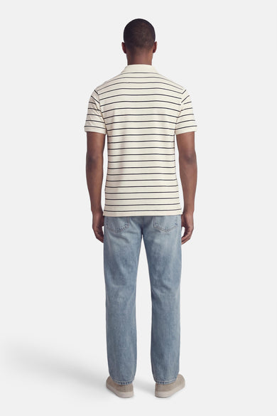Wit gestreept poloshirt van Levi's®, gedragen met een blauwe spijkerbroek en casual suède schoenen, achtergezicht.