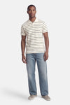 Wit poloshirt met zwarte strepen van Levi's®, gedragen met een blauwe spijkerbroek en grijze sneakers.