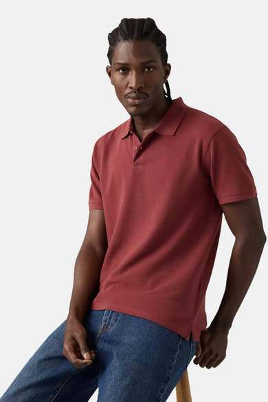 Polo bordeaux à manches courtes de Levi's®, porté avec un jean bleu et tresses visibles.
