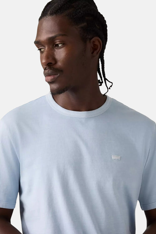 T-shirt bleu clair à manches courtes de Levi's, porté par un homme avec des tresses.
