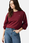 Burgundy crewneck sweatshirt by Levi's with small chest logo, worn with blue jeans, side view
