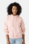 Soft pink oversized hoodie with front pocket and drawstrings, worn by model with light blue jeans, front view