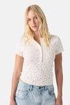 White short-sleeve floral print t-shirt with button placket and ribbed texture, worn with light blue jeans, front view