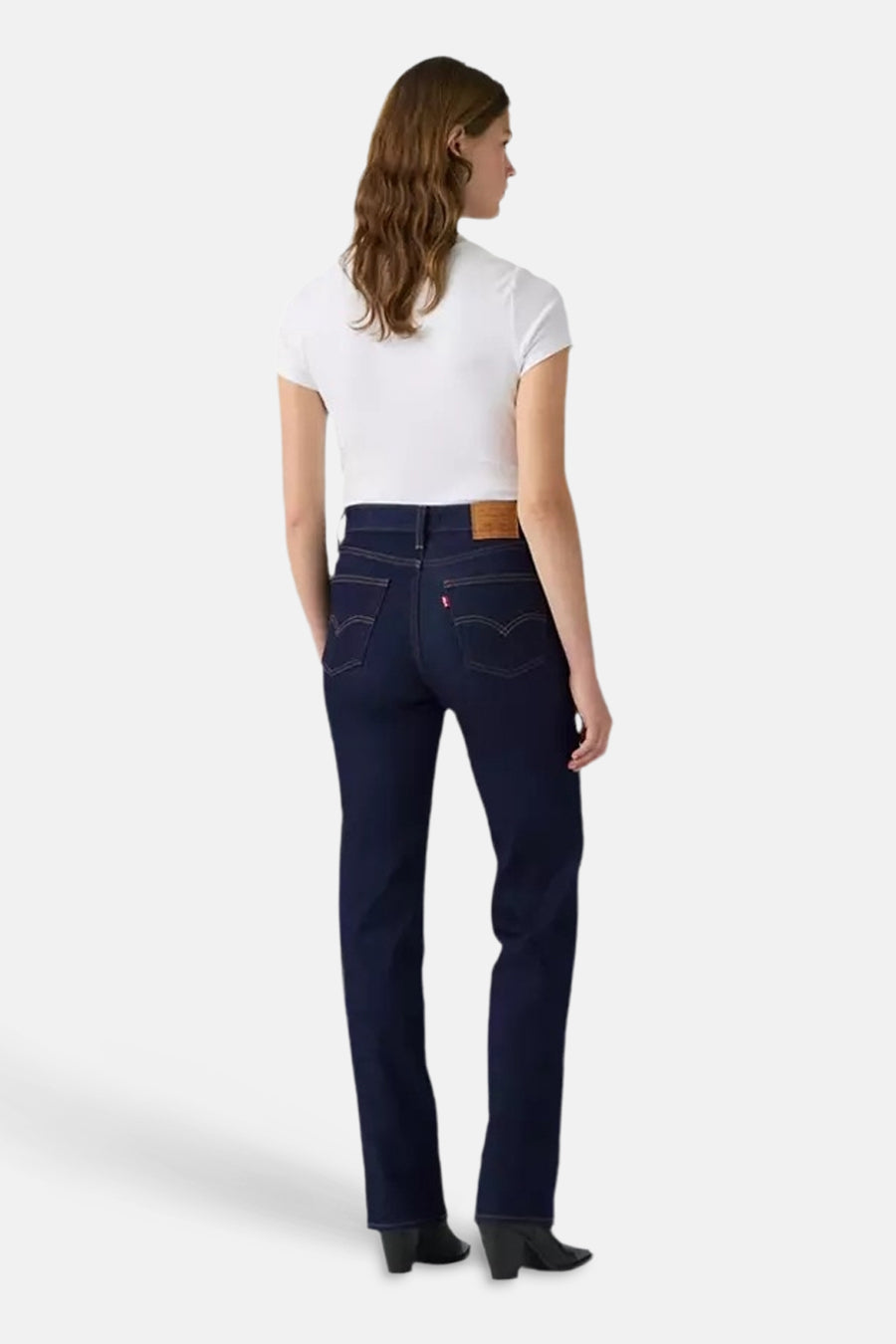 Dark blue straight-leg denim jeans by Levi's, back view with classic stitching and leather waistband patch, worn with white top and black boots