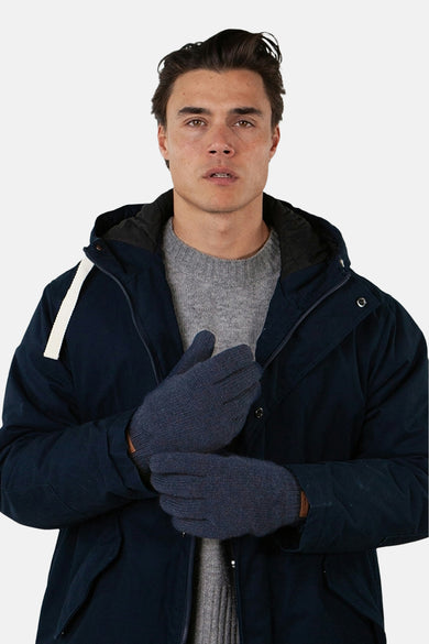 Blauwe handschoenen van BARTS gedragen met een marineblauwe winterjas en een grijze trui.