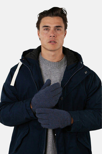 Blauwe handschoenen van BARTS gedragen met een marineblauwe winterjas en een grijze trui.