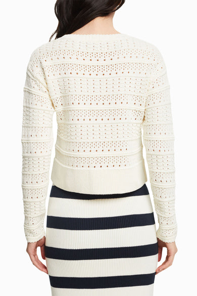 Pull écru col rond d'Esprit, avec motifs ajourés et rayures horizontales, porté avec une jupe rayée.
