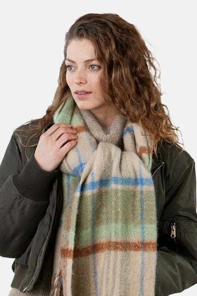 Écharpe à carreaux en vert et beige de BARTS, portée avec un manteau kaki et un pull en maille neutre.
