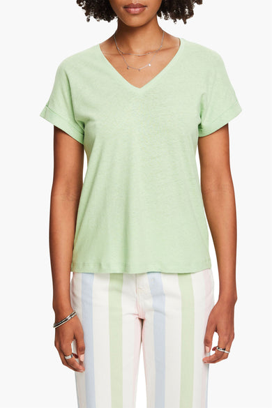 Top vert en jersey par Esprit, porté avec un pantalon rayé pastel et un collier argenté.
