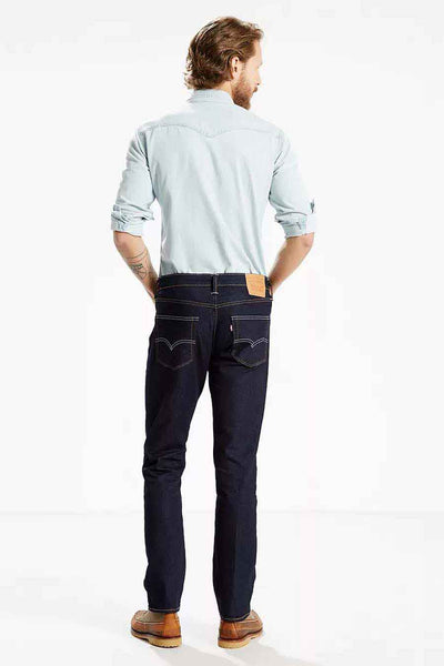 Dark blue slim-fit denim jeans by 511™, back view with contrast stitching and leather waistband patch, worn with light blue shirt and brown boots