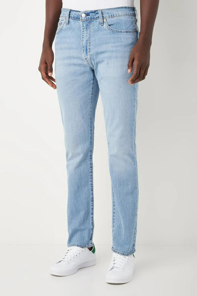 Jean slim en denim bleu clair de Levi's, coupe décontractée, porté avec des baskets blanches.