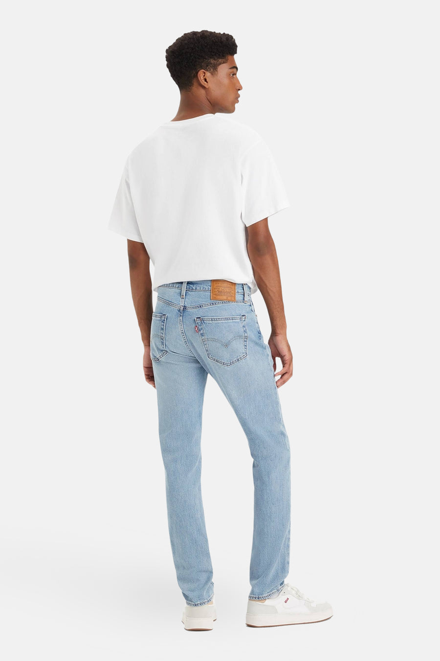 Jean slim en denim bleu clair de Levi's, porté avec un t-shirt blanc et des baskets blanches.