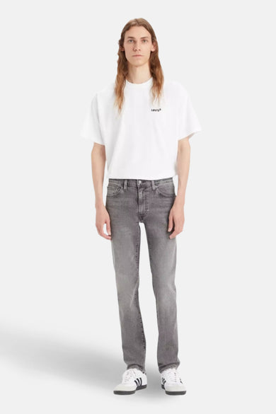 Jean slim gris clair de Levi's, porté avec un t-shirt blanc uni et des chaussures de sport blanches.
