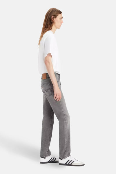 Jean slim en denim gris clair de Levi's, vue de côté, porté avec un t-shirt blanc et des baskets.