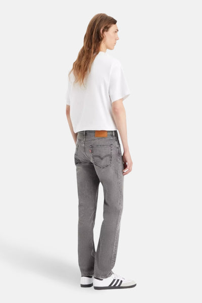Jean slim gris clair de Levi's, porté avec un t-shirt blanc et des baskets à rayures, vue de dos.
