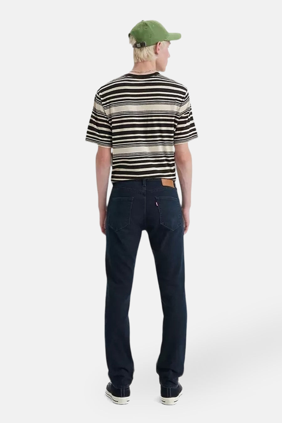 Jean slim en denim bleu foncé de Levi's, porté avec un t-shirt rayé et une casquette verte.