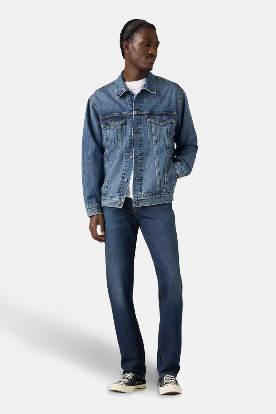 Slim jeans in donkerblauw denim van Levi's, gedragen met een spijkerjack en zwarte sneakers.