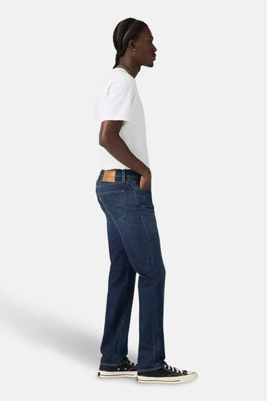 Slim jeans in donkerblauw denim van Levi's, gedragen met een effen wit T-shirt en zwarte hoge sneakers.