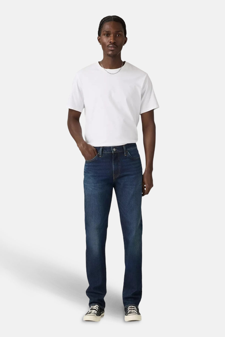 Donkerblauwe slim fit jeans van Levi's, gedragen met een wit T-shirt en sneakers met patroon.