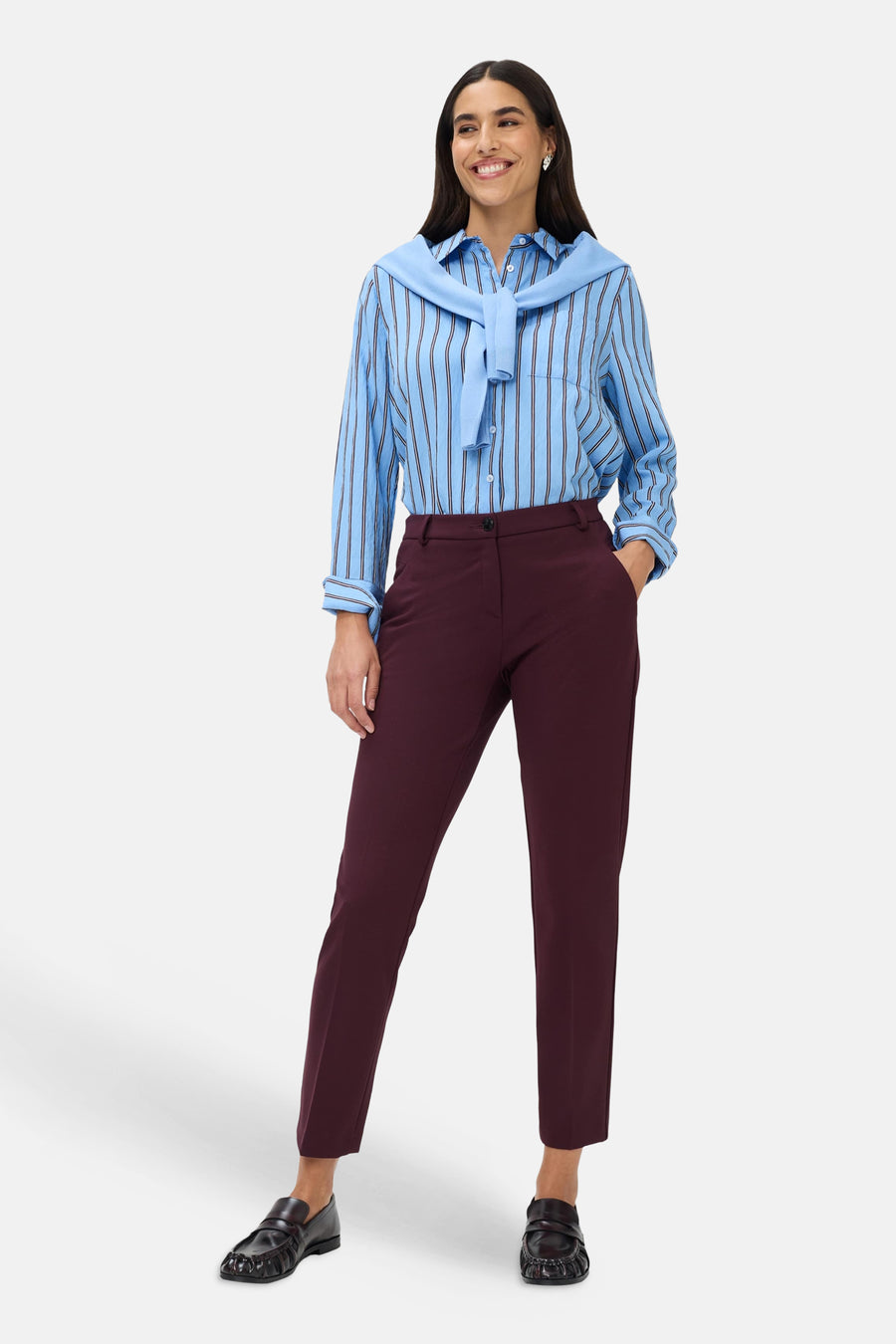 Chino rouge foncé BRAX porté par une mannequin, avec une chemise rayée bleue et des mocassins noirs.