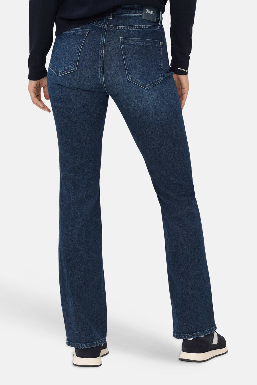 Mid blue denim bootcut jeans by BRAX, back view with classic stitching and flared legs, worn with dark top and sneakers.