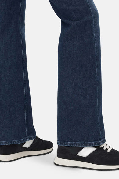 Mid blue denim bootcut jeans by BRAX, side view showing flared leg and hem detail with black sneakers.