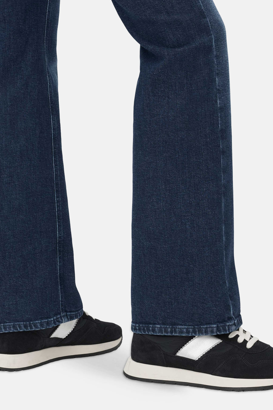 Mid blue denim bootcut jeans by BRAX, side view showing flared leg and hem detail with black sneakers.