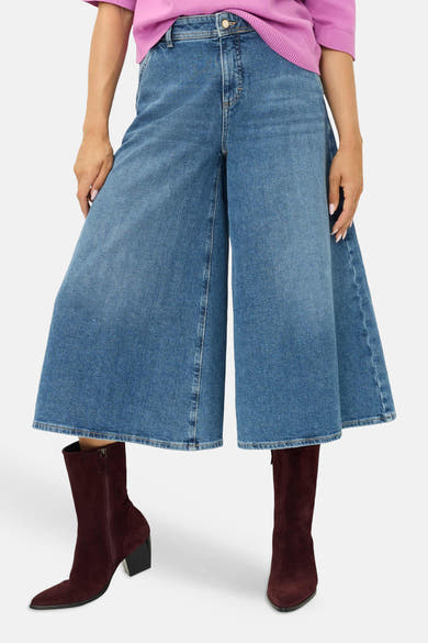 Jean large bleu clair en denim BRAX, porté avec un pull rose et des bottes bordeaux