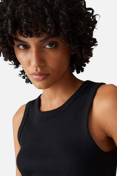 Top noir côtelé sans manches de OPUS, porté par une femme aux cheveux bouclés.