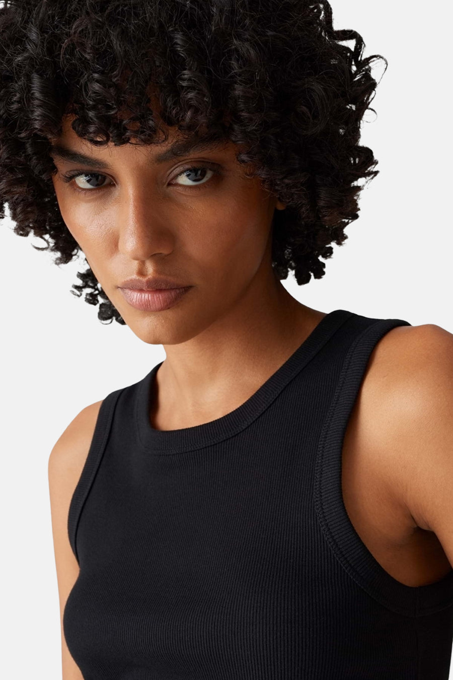 Top noir côtelé sans manches de OPUS, porté par une femme aux cheveux bouclés.