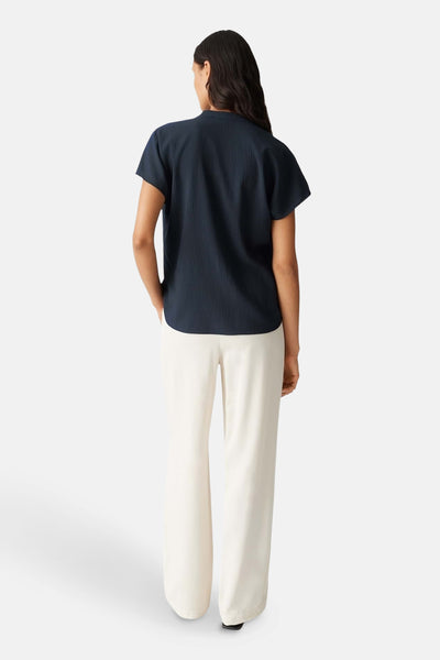 Donkerblauwe blouse met korte mouwen van OPUS, met een wafelstructuur, gedragen met een witte broek.