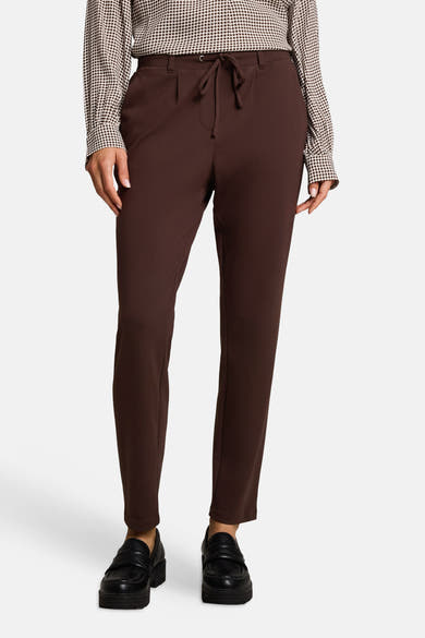 Brown five-pocket women's trousers with drawstring waist, front view, paired with polka-dot blouse and black loafers