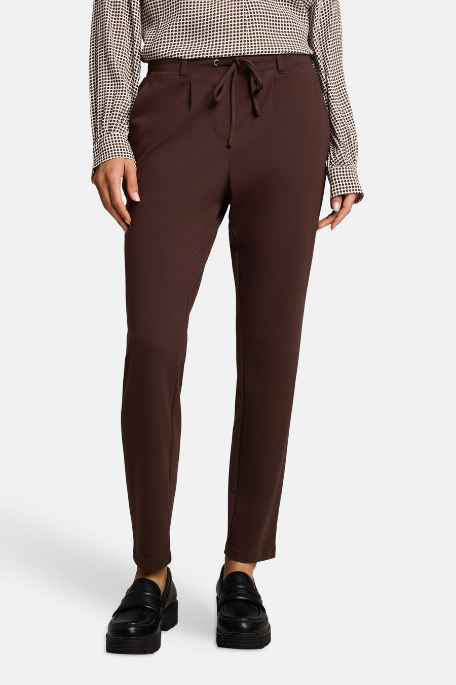 Brown five-pocket women's trousers with drawstring waist, front view, paired with polka-dot blouse and black loafers