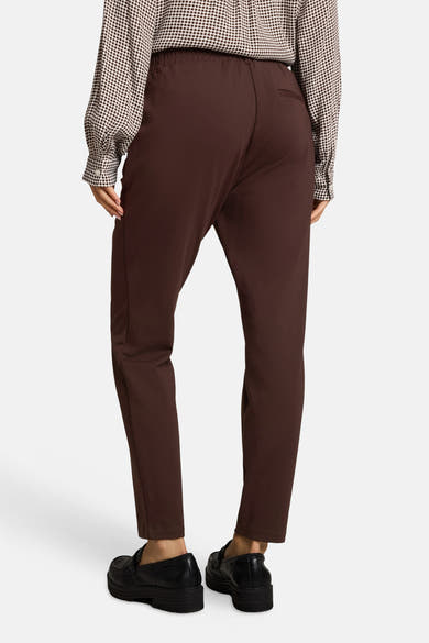 Brown five-pocket women's seasonal trousers with elastic waist, back view, paired with polka-dot blouse and black loafers