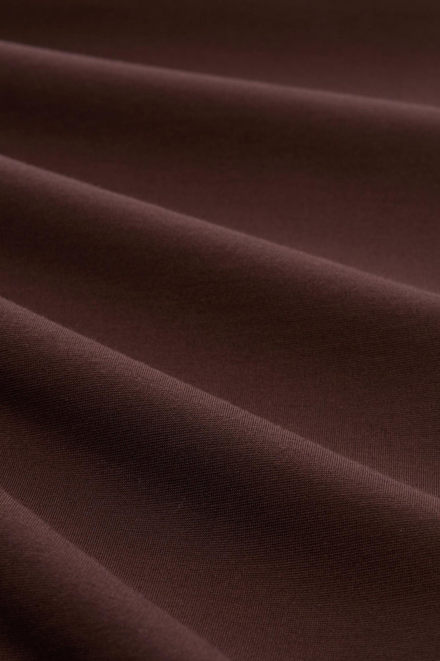 Brown five-pocket women's seasonal trouser fabric close-up, soft textured material with gentle folds and rich color tone